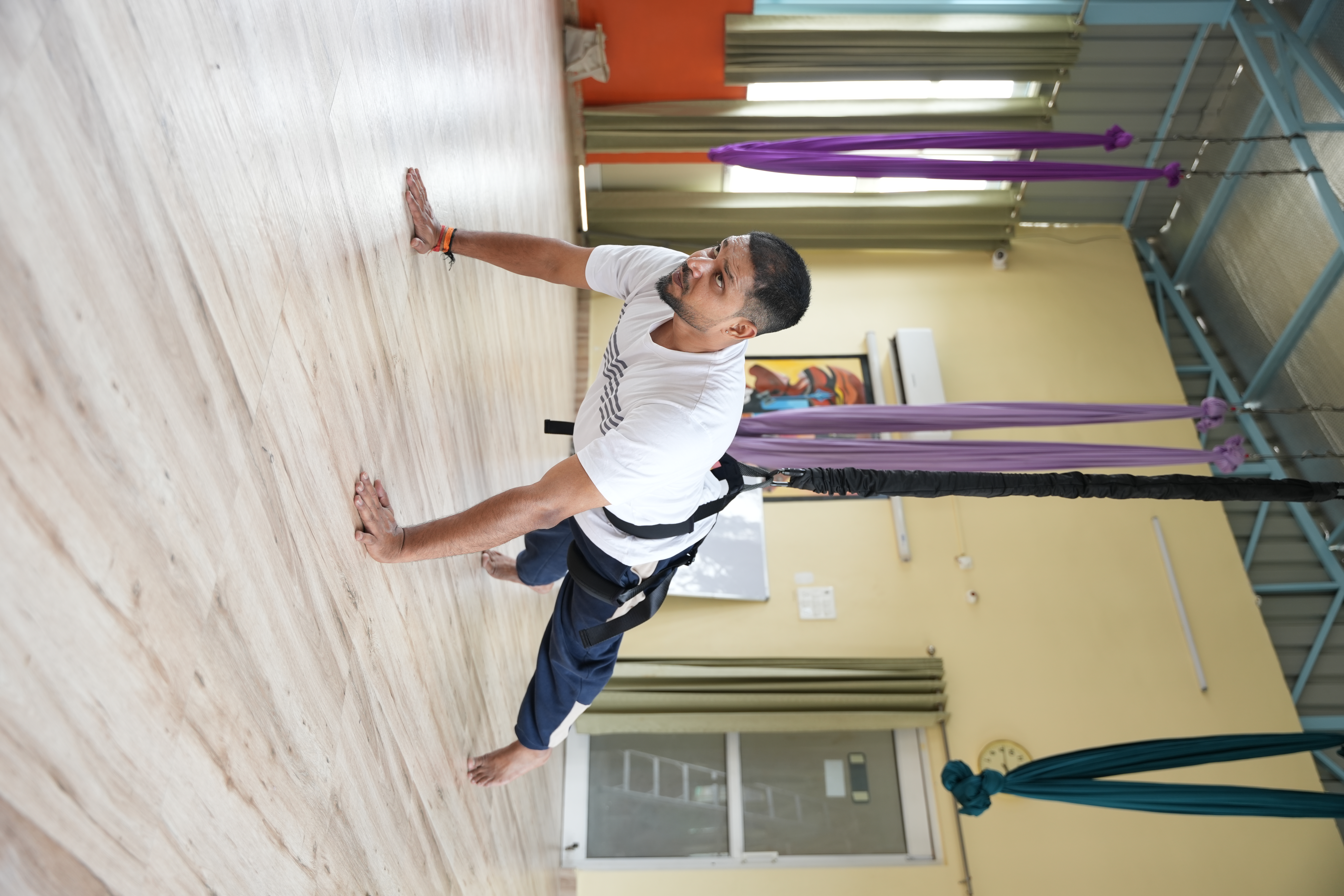 Practitioner performing a graceful aerial yoga pose in soft studio light